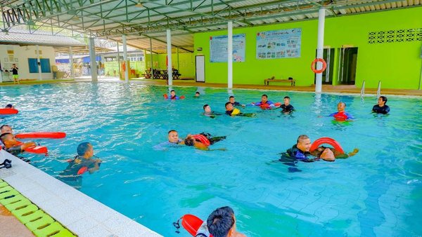 Lifeguard trainees practicing rescue skills in a swimming pool