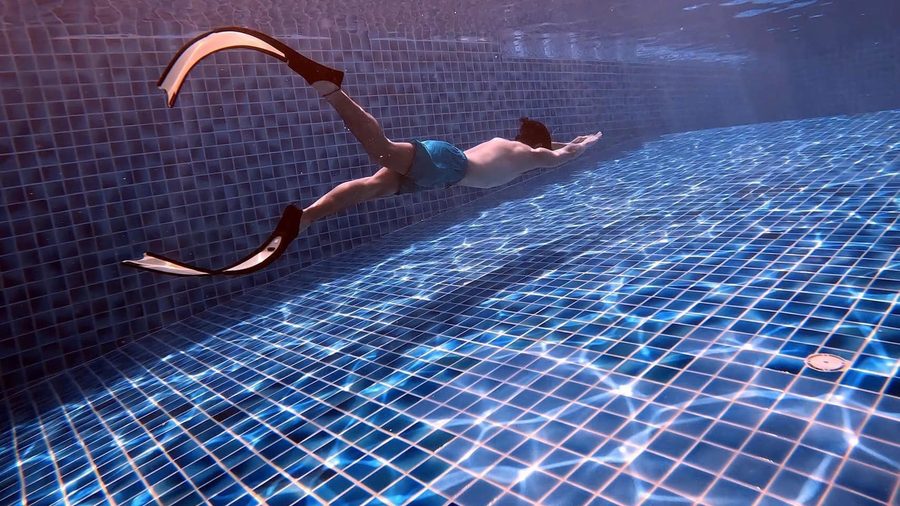 Mermaid-style pool training with long fins in a tiled pool