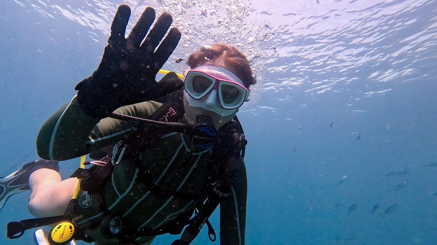 Scuba diver waving calmly in clear blue water