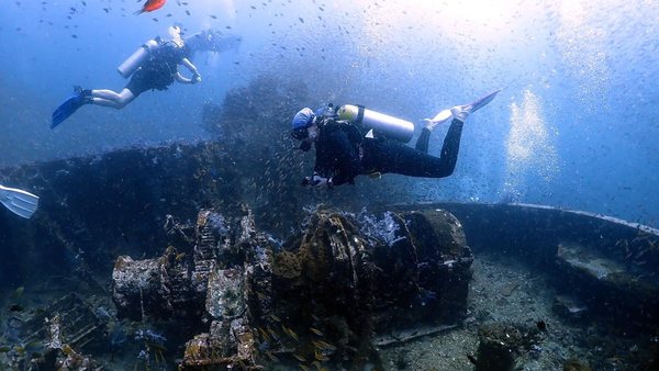 Two scuba divers exploring an underwater wreck structure