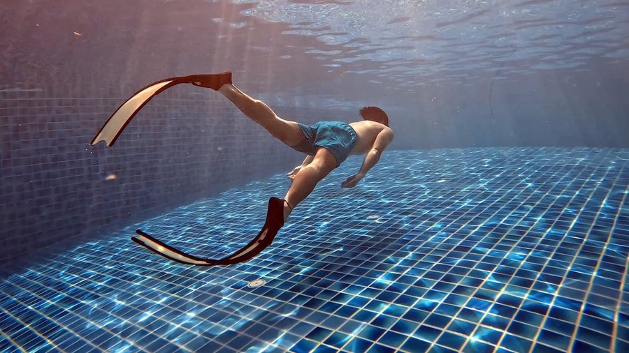 Mermaid-style pool fin practice in clear blue water