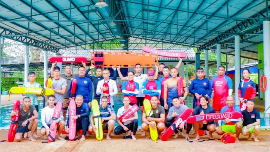Lifeguard trainees gathered with rescue equipment beside a pool
