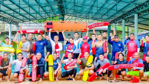 Water-safety trainees with lifeguard rescue equipment at a pool
