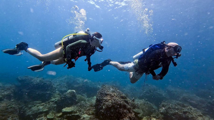 Two divers swimming together in clear water during supervised scuba training