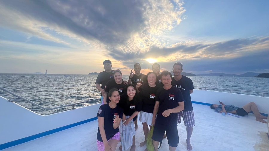 Dive group smiling together on a boat at sunset
