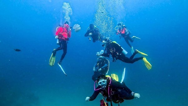 Group of scuba divers swimming together in blue water